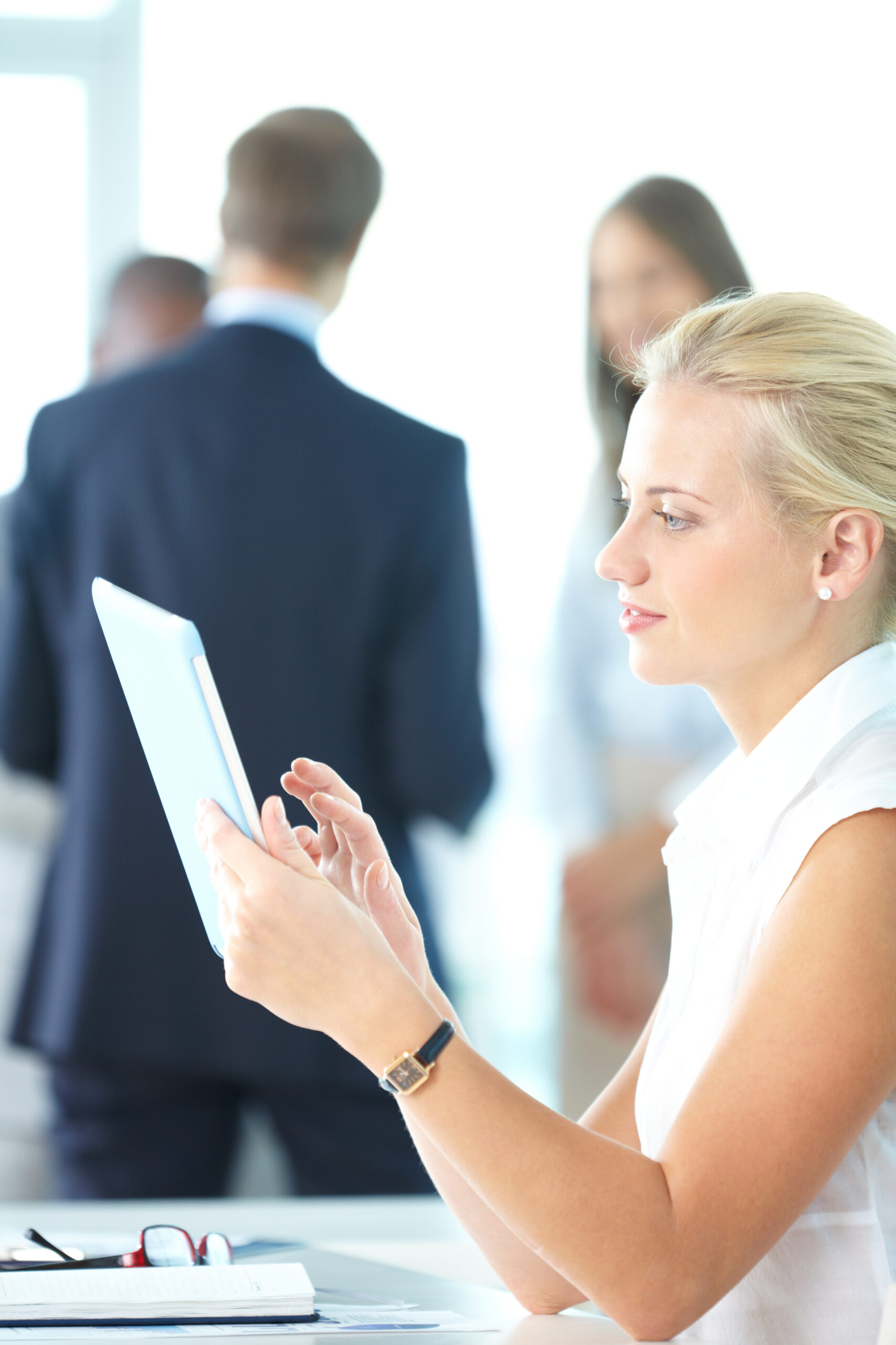 businesswoman-using-her-digital-tablet-with-businesspeople-blurred-background-scaled.jpg